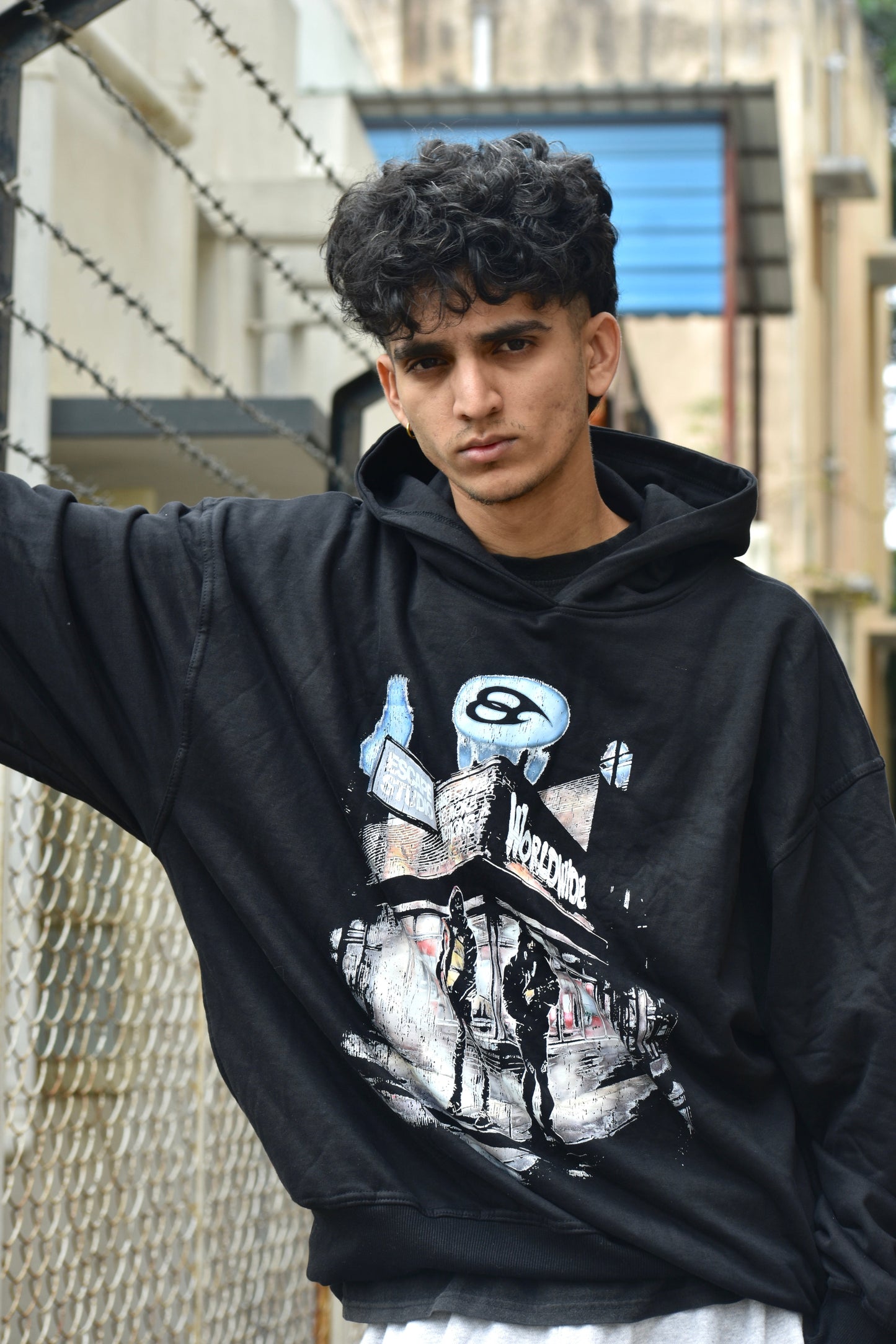 Person wearing a black hoodie with graphic design, standing outdoors.